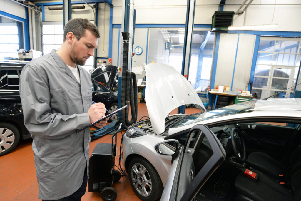 TÜV Prüfer bei der Hauptuntersuchung in einer Werkstatt