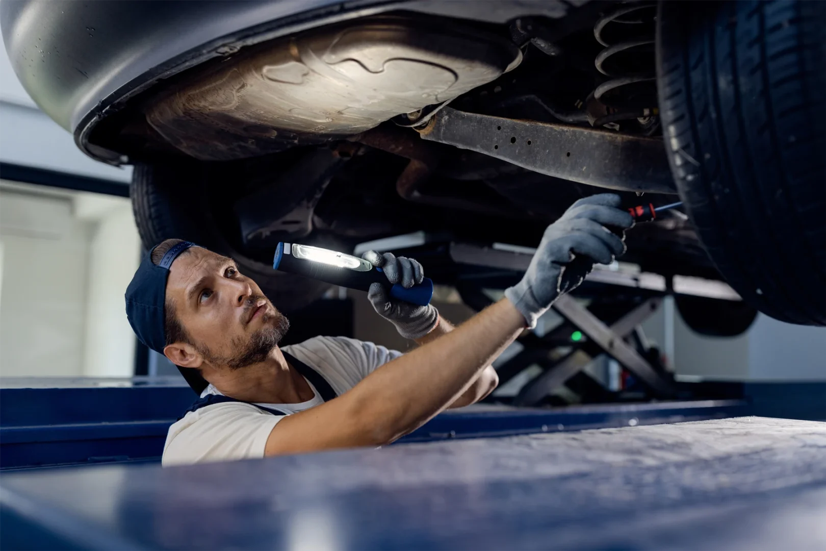 Kfz-Mechatroniker untersucht das Fahrwerk unter dem Auto