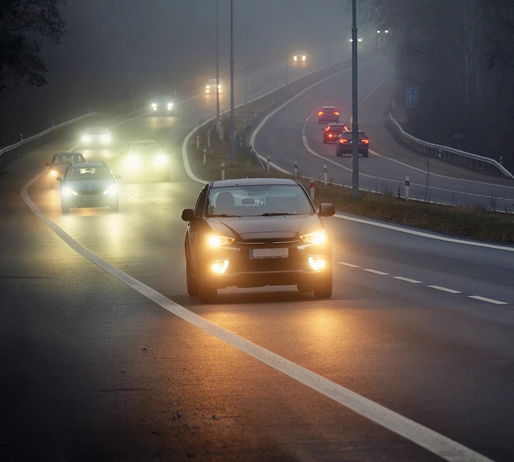 Autos mit Scheinwerfer an auf einer Autobahn im Herbst